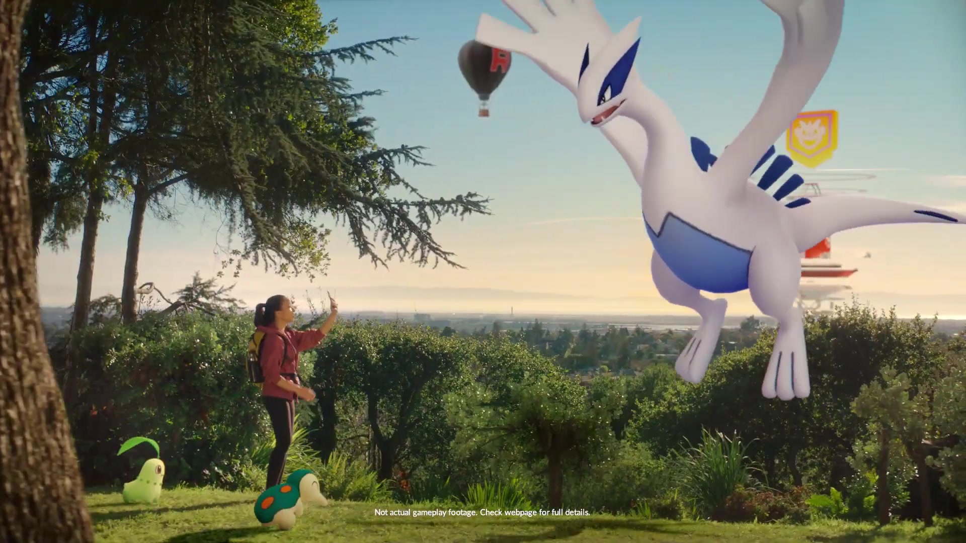 Lugia towers above a trainer in a wooded landscape